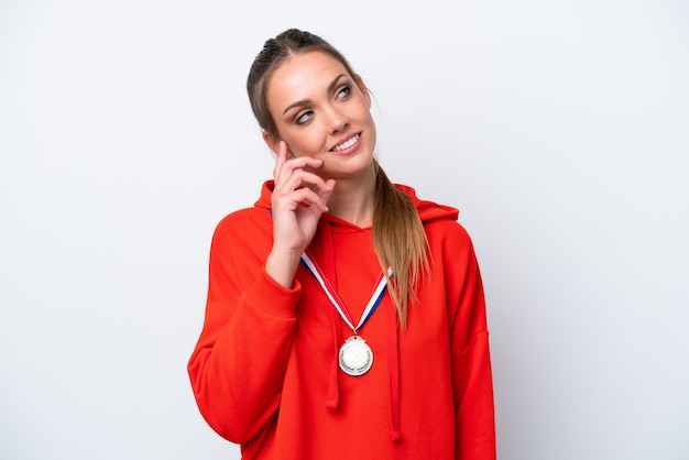 Young caucasian woman with medals isolated on white background thinking an idea