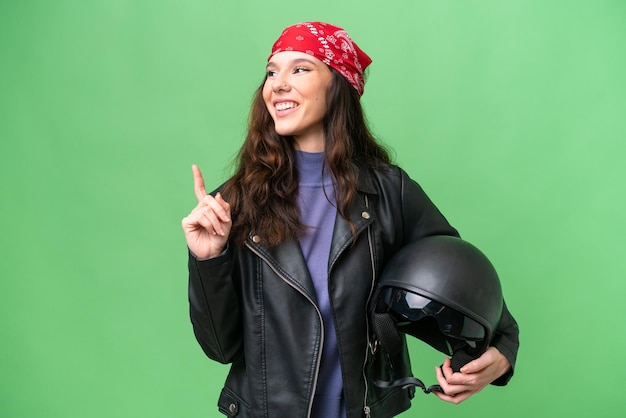 Foto giovane donna caucasica con un casco da moto su uno sfondo isolato che indica una grande idea