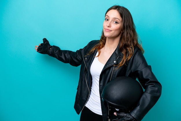 Young caucasian woman with a motorcycle helmet isolated on blue background extending hands to the side for inviting to come