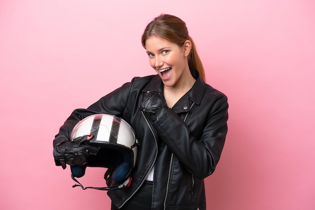 Young caucasian woman with a motorcycle helmet isolated on pink\
background celebrating a victory