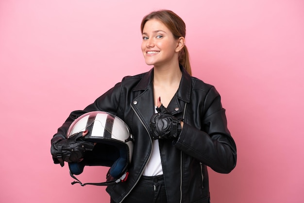 Young caucasian woman with a motorcycle helmet isolated on pink background giving a thumbs up gesture