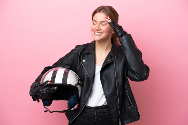 Young caucasian woman with a motorcycle helmet isolated on pink background smiling a lot