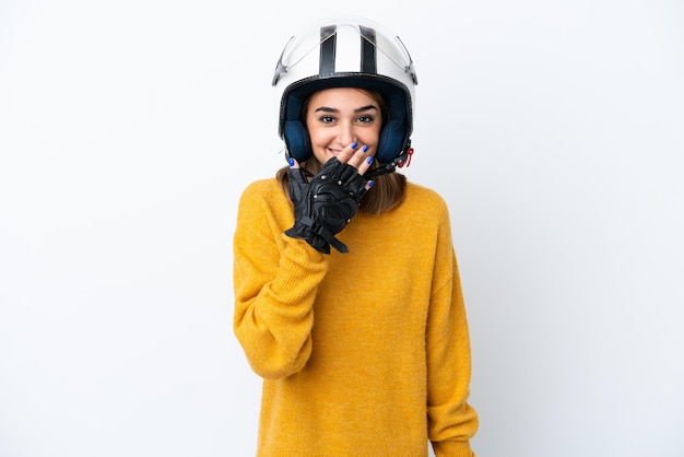 Молодая кавказская женщина в мотоциклетном шлеме на белом фоне счастлива и улыбается, прикрывая рот рукой
