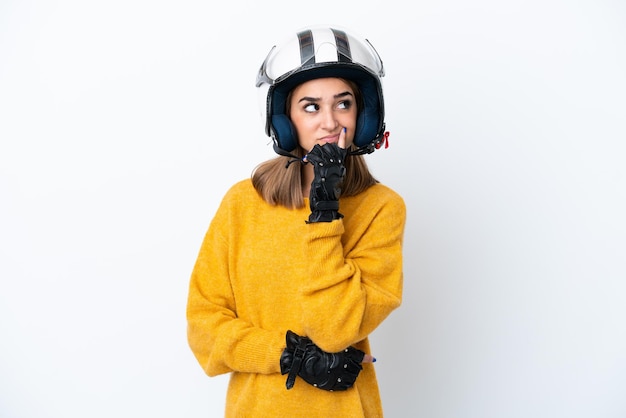 Young caucasian woman with a motorcycle helmet isolated on white background having doubts while looking up