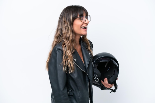 Young caucasian woman with a motorcycle helmet isolated on white background laughing in lateral position