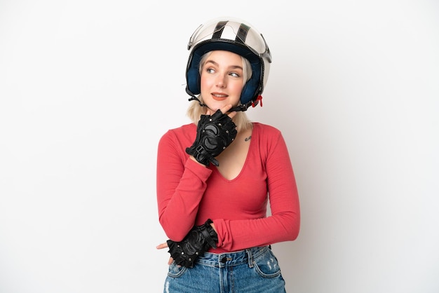 Young caucasian woman with a motorcycle helmet isolated on white background looking up while smiling
