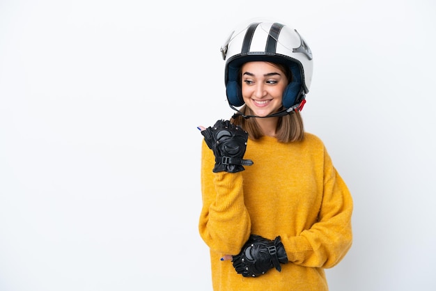 Young caucasian woman with a motorcycle helmet isolated on white background pointing to the side to present a product