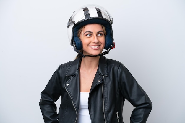 Young caucasian woman with a motorcycle helmet isolated on
white background posing with arms at hip and smiling