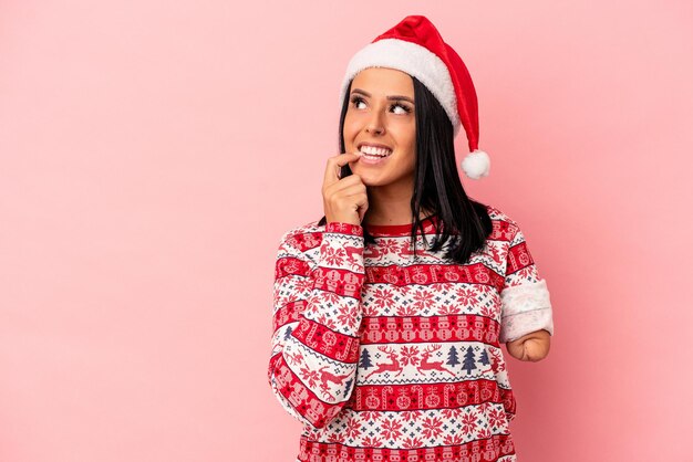 Young caucasian woman with one arm celebrating Christmas isolated on pink background relaxed thinking about something looking at a copy space.