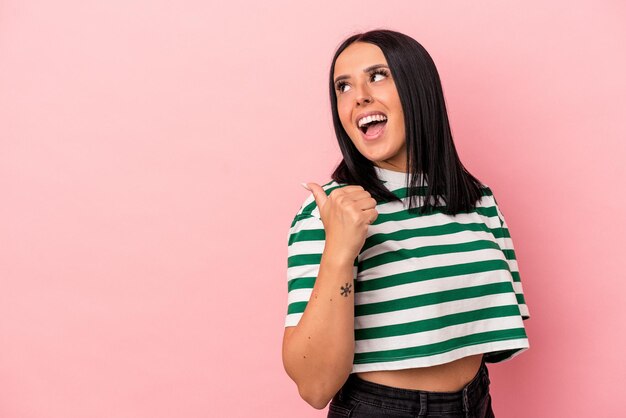 Young caucasian woman with one arm isolated on pink background points with thumb finger away, laughing and carefree.