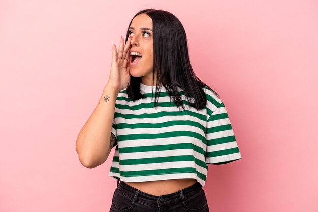 Young caucasian woman with one arm isolated on pink background shouting and holding palm near opened mouth.