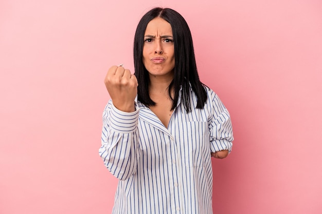 Foto giovane donna caucasica con un braccio isolato su sfondo rosa che mostra il pugno alla telecamera, espressione facciale aggressiva.