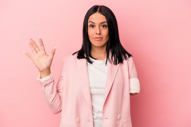 Young caucasian woman with one arm isolated on pink background smiling cheerful showing number five with fingers.