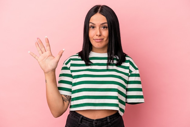 Young caucasian woman with one arm isolated on pink background smiling cheerful showing number five with fingers.