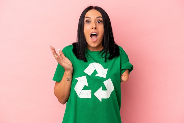 Young caucasian woman with one arm recycled waste isolated on pink background surprised and shocked.