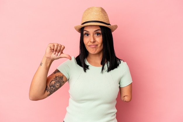 Young caucasian woman with one arm wearing a summer hat isolated on pink background showing a dislike gesture, thumbs down. Disagreement concept.