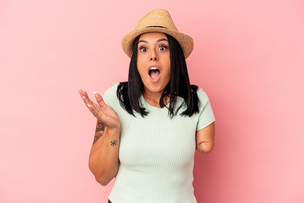 Young caucasian woman with one arm wearing a summer hat isolated on pink background surprised and shocked.