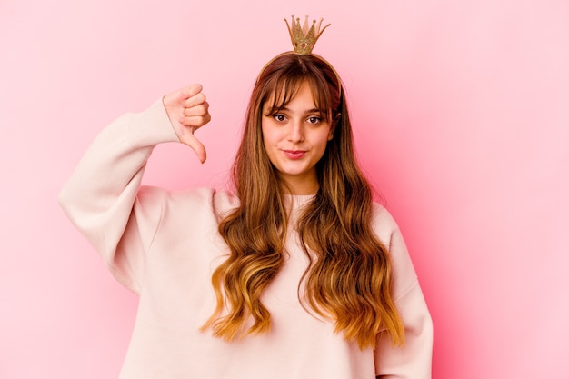 Young caucasian woman with princess crown isolated showing a dislike gesture, thumbs down. Disagreement concept.