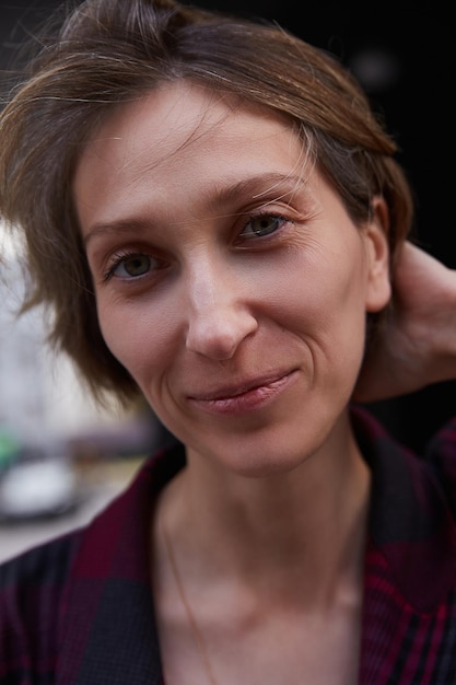 Young caucasian woman with short hair in red checkered jacket outdoors at street