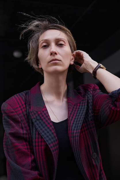 Young caucasian woman with short hair in red checkered jacket outdoors at street