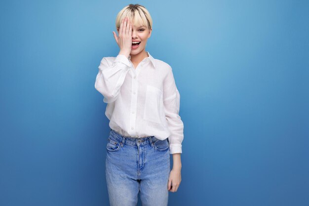 Young caucasian woman with a short haircut is dressed in a white shirt on background with copy space