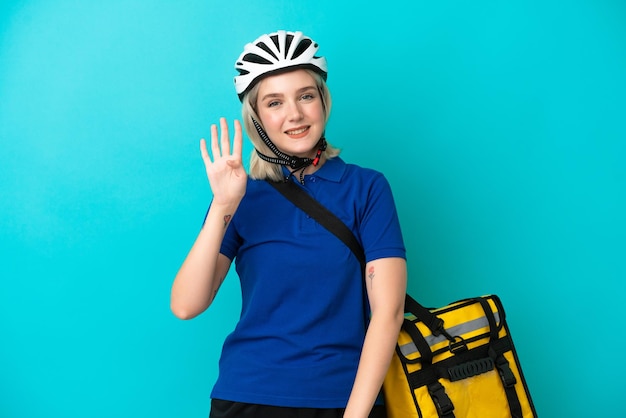 Young caucasian woman with thermal backpack isolated on blue background happy and counting four with fingers