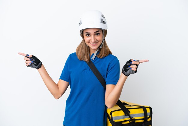 Young caucasian woman with thermal backpack isolated on white background pointing finger to the laterals and happy