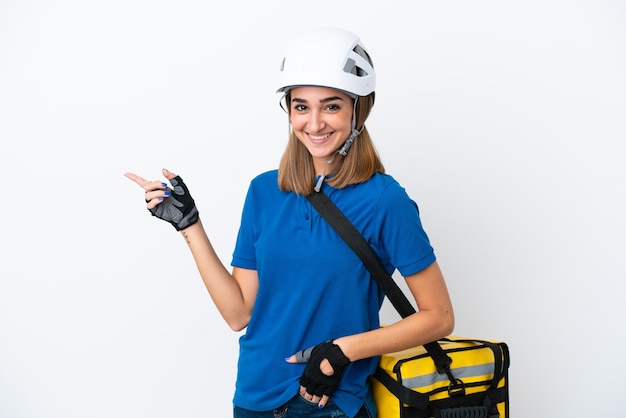 Young caucasian woman with thermal backpack isolated on white background pointing finger to the side and presenting a product