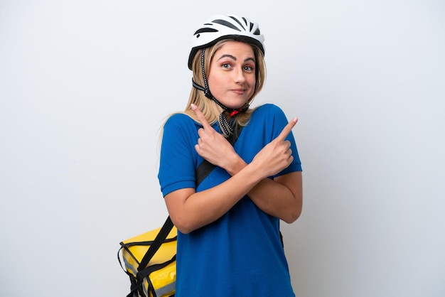 Young caucasian woman with thermal backpack isolated on white background pointing to the laterals having doubts