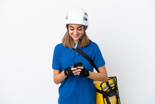 Young caucasian woman with thermal backpack isolated on white background sending a message with the mobile