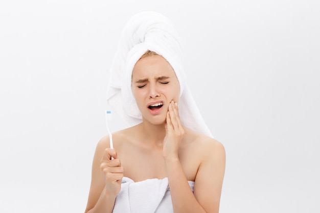 Young caucasian woman with toothache while brushing her teeth