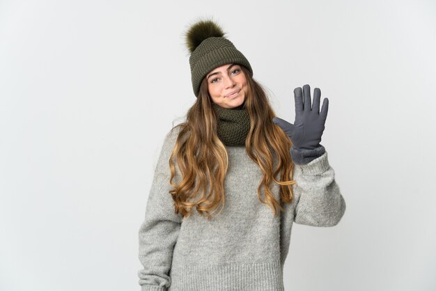 指で5を数える白い壁に分離された冬の帽子を持つ若い白人女性
