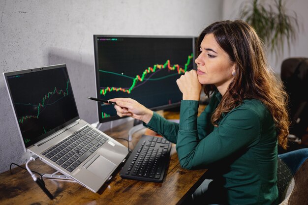 Young caucasian woman working at office desk studying charts. Attractive woman with serious face at office desk.