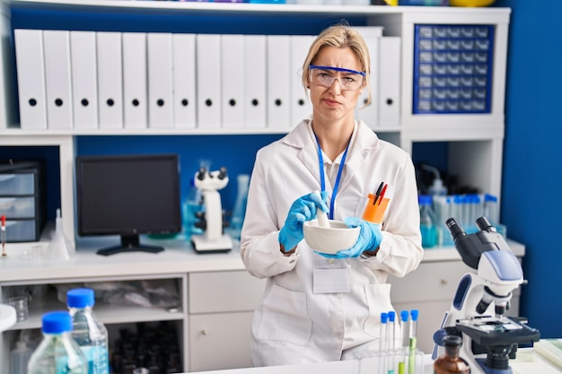 Young caucasian woman working at scientist laboratory skeptic and nervous, frowning upset because of problem. negative person.