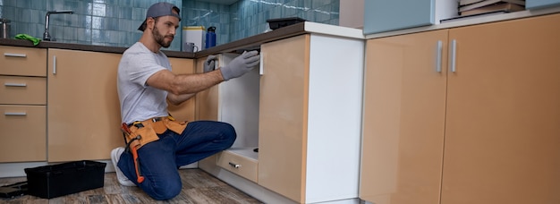 Young caucasian worker measuring drawer in kitchen furniture