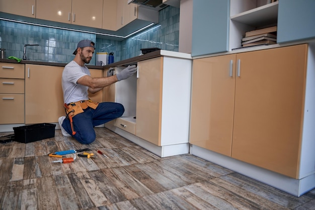 Young caucasian worker measuring drawer in kitchen furniture