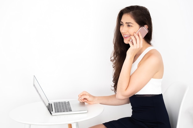 Foto giovane donna caucasica di affari che parla sul telefono e che lavora al computer portatile