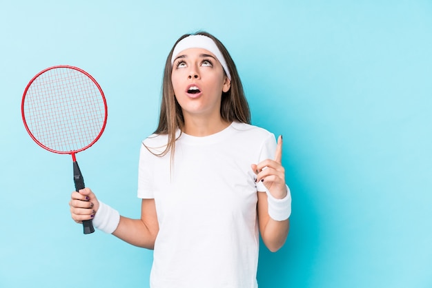 Young caucasic woman playing badminton isolated pointing upside with opened mouth.