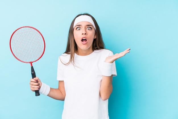 Young caucasic woman playing badminton isolated surprised and shocked.