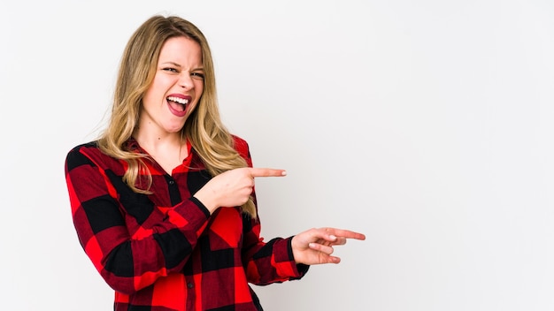 Young cauciasian woman isolated on white background pointing with forefingers to a copy space, expressing excitement and desire.