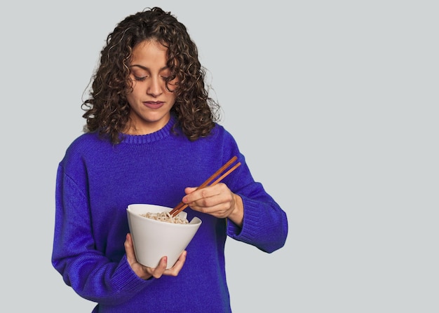 A young caucsian woman eating noddles with chopsticks very happy