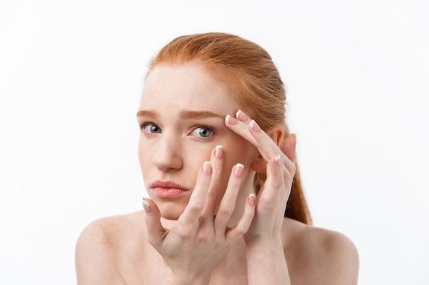 Giovane donna caucsiana stringe l'acne sul volto della bellezza