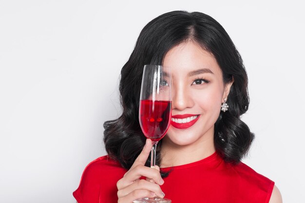 와인 잔을 들고 빨간 드레스에 젊은 축 하 아시아 여자