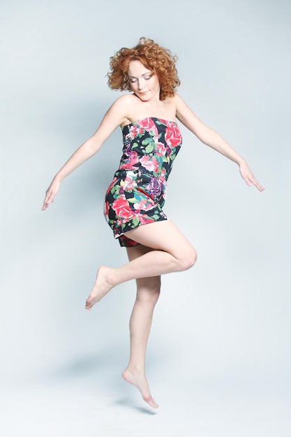 Young charming female in dress jumping