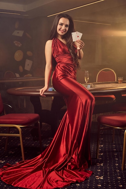 Молодая очаровательная женщина позирует за покерным столом в vip казино.