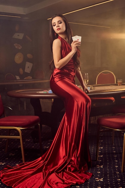 Молодая очаровательная женщина позирует за покерным столом в vip казино.