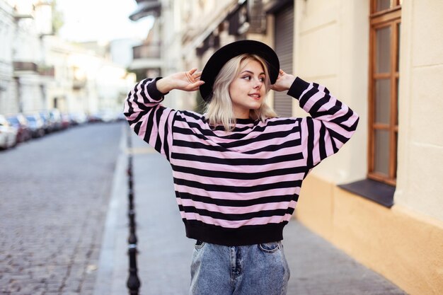 Foto young charming girl in a hat is walking along a european street