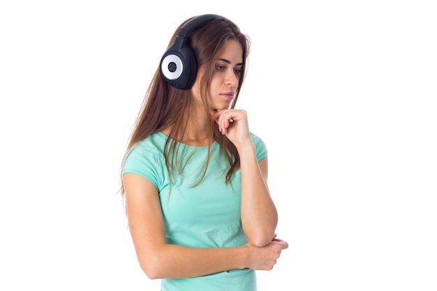 Young charming woman in blue Tshirt listening to the music in black headphones in studio