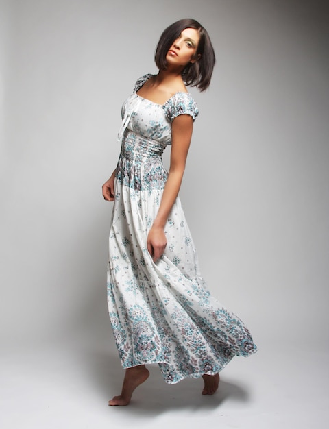 Young charming woman in chiffon dress jumping over grey backgro