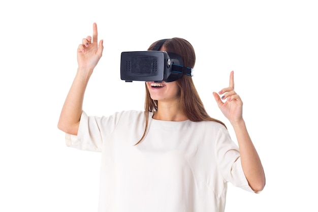 Young charming woman in white shirt using virtual reality glasses on white background in studio